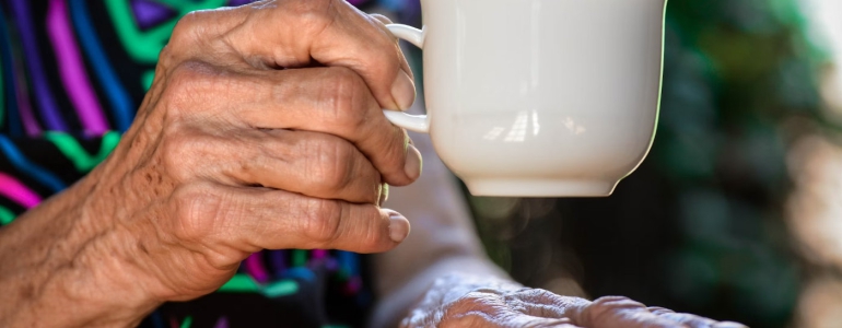 Photo of older hands holding a tea cup.