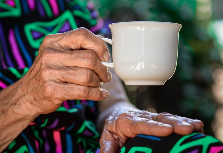Photo of older hands holding a tea cup.