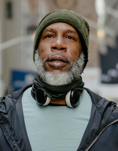 Photo of an older man wearing headphones and a green beanie