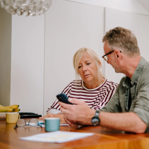 An older man and woman sit at a table talking.