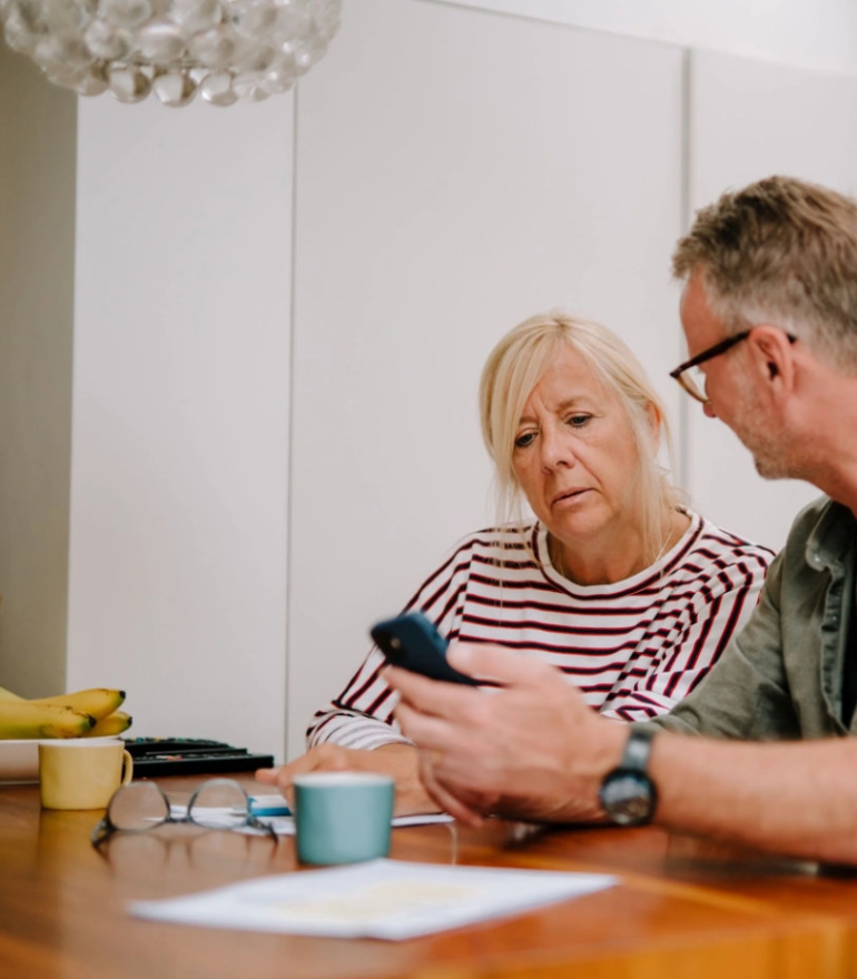 An older man and woman sit at a table talking.