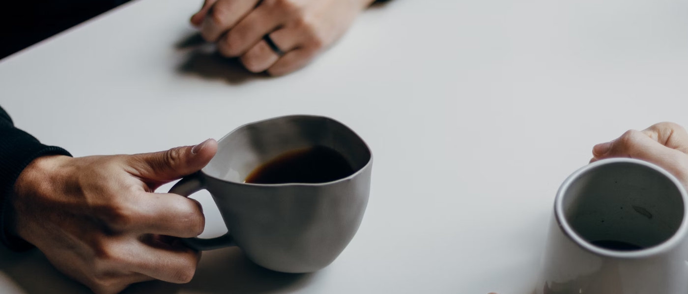 A table, hands and cups of coffee.