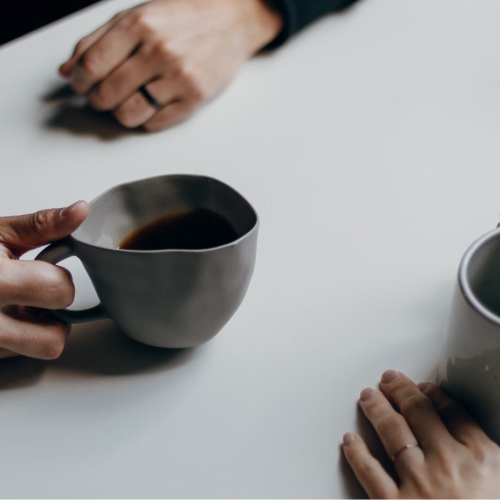 A table, hands and cups of coffee.