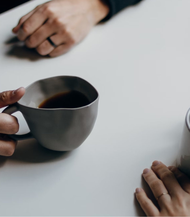 A table, hands and cups of coffee.