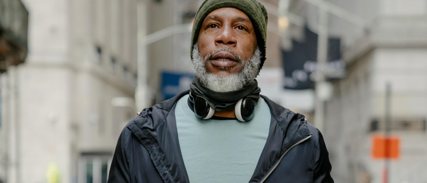 An older man wearing headphones and green beanie hat