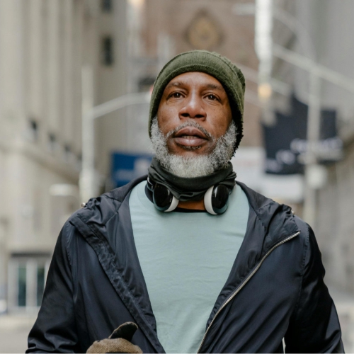 An older man wearing headphones and green beanie hat