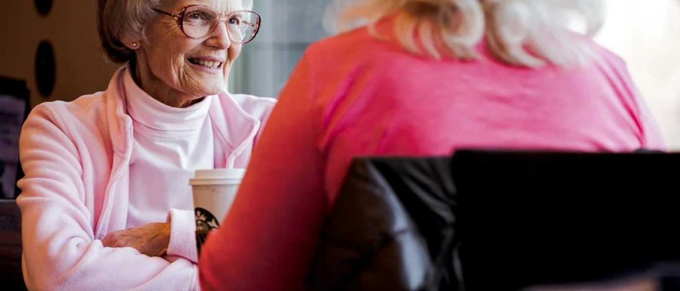 Two women sit at a restaurant table chatting.