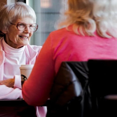 Two women sit at a restaurant table chatting.