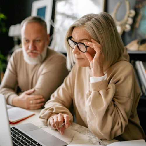 An older man and woman view a laptop computer