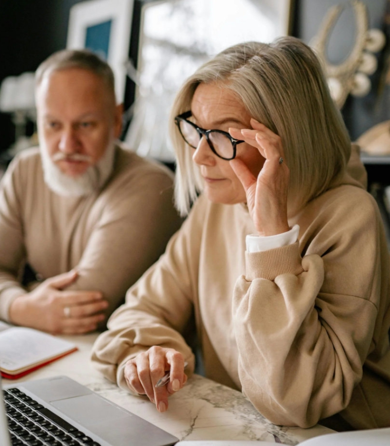 An older man and woman view a laptop computer