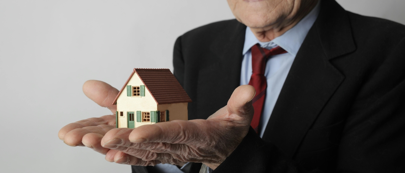 Elderly Man with small house in his hands